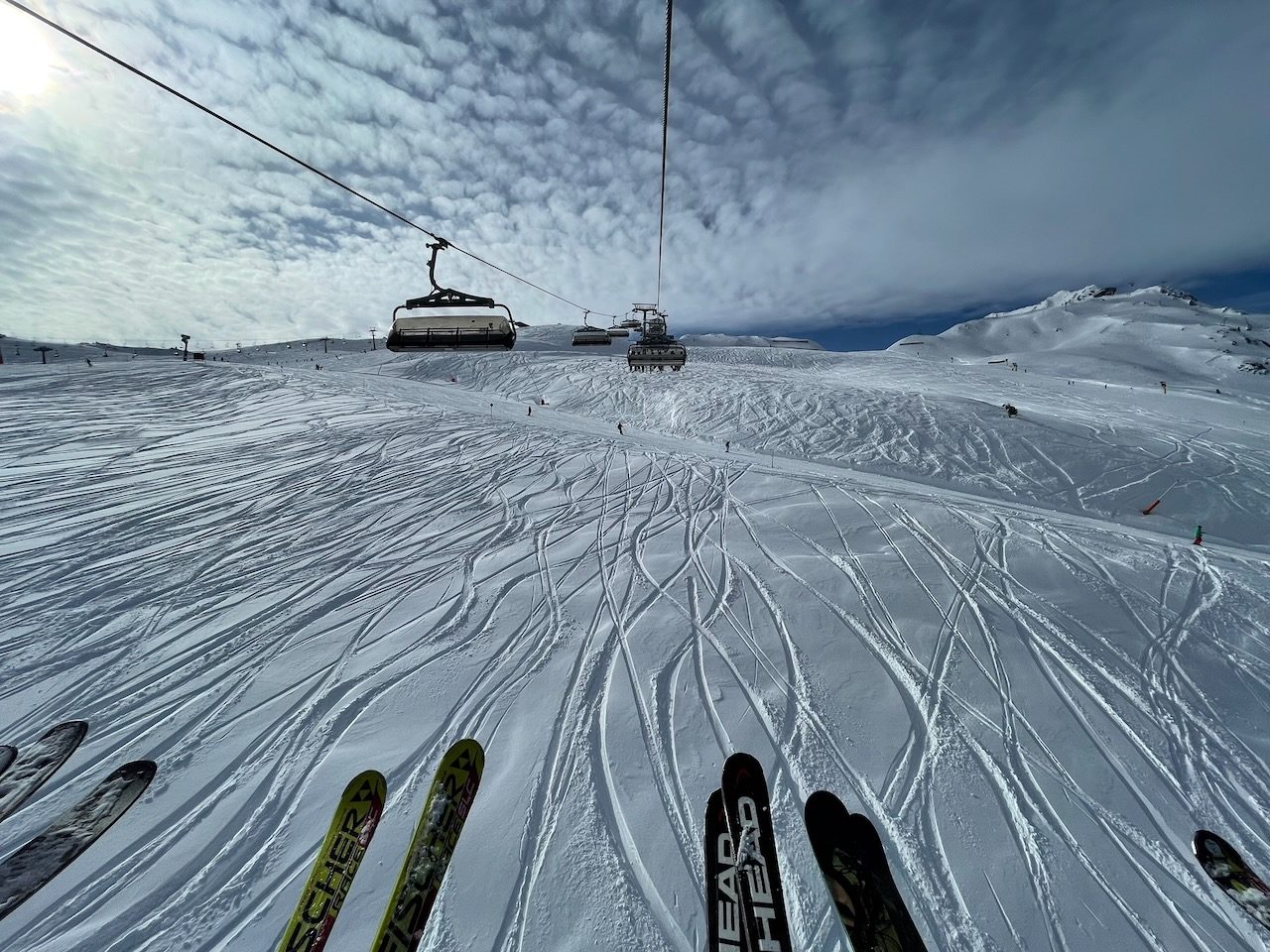 Blick vom Sessellift auf Skispitzen und eine verspurte Piste